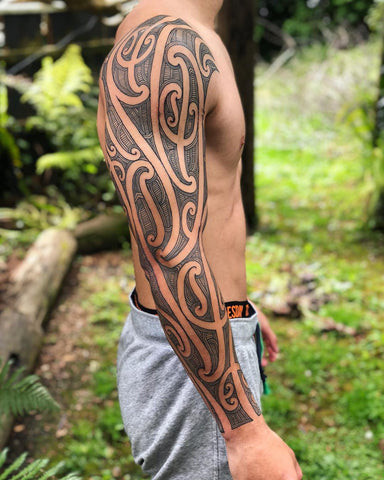 Patterned sleeve tattoo on a man's arm, featuring geometric and tribal-inspired patterns in black ink