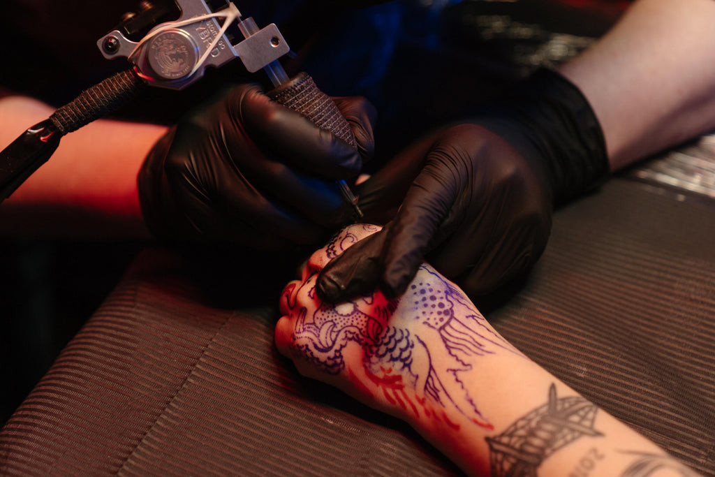 Close-up of a fresh tattoo on a person's arm, showcasing the redness and slight swelling typical of new tattoos.