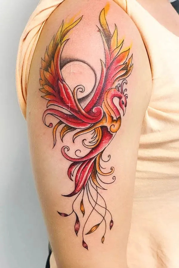 Colorful phoenix tattoo with vibrant wings and flowing tail feathers on a person