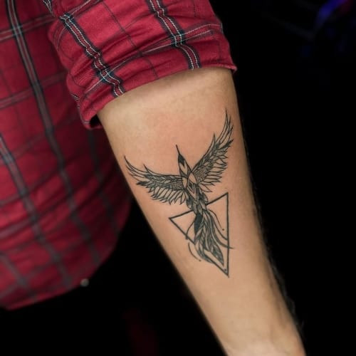 Two phoenix tattoos on men, one on the forearm with a realistic phoenix in flight and another on the arm with a minimalist phoenix outline.