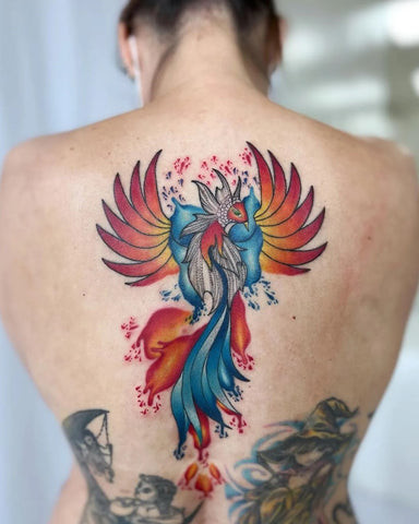 Vibrant phoenix back tattoo for men, wings ablaze in reds and oranges, symbolizing rebirth and resilience.