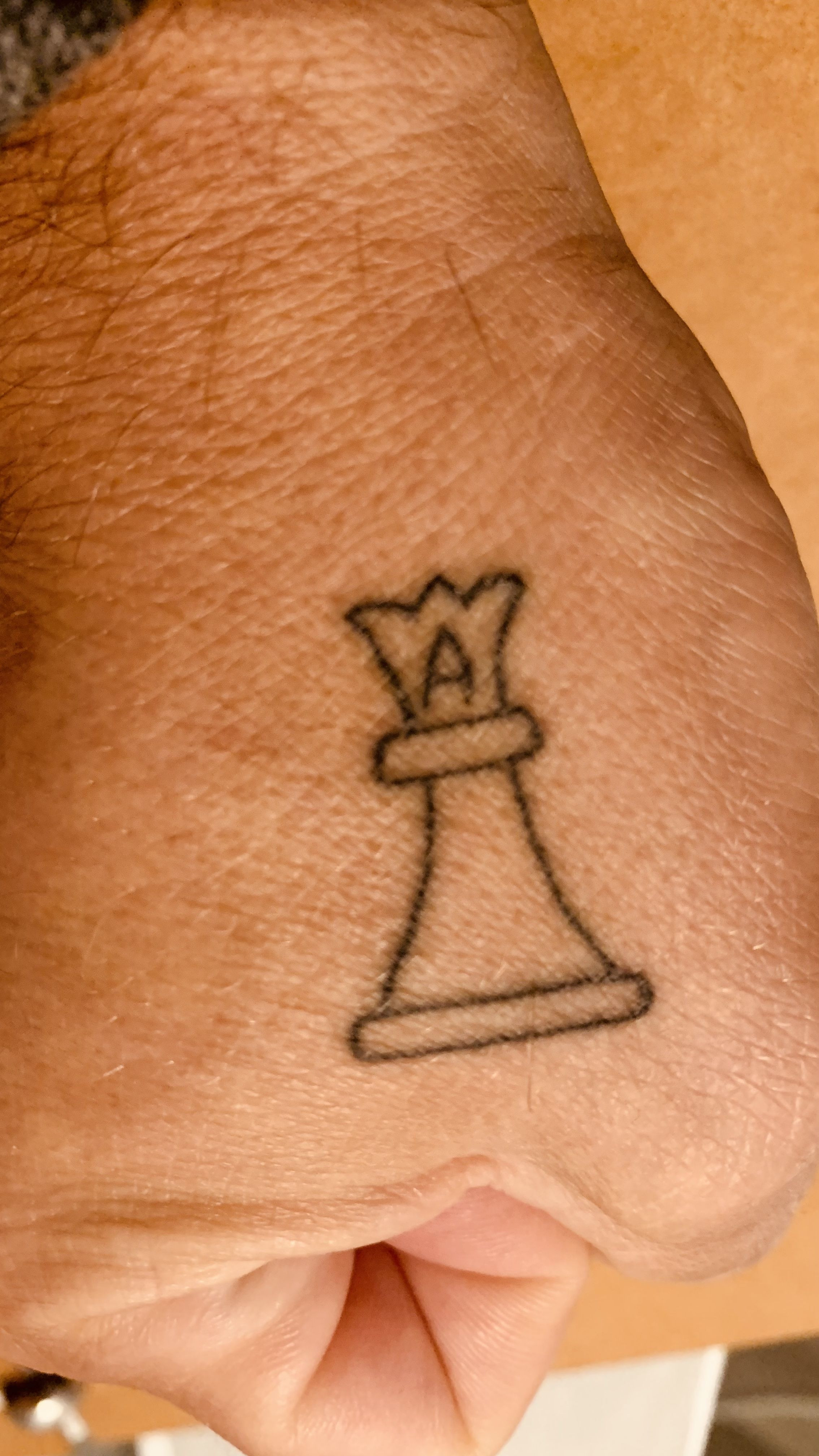 Minimalist queen chess piece tattoo on wrist