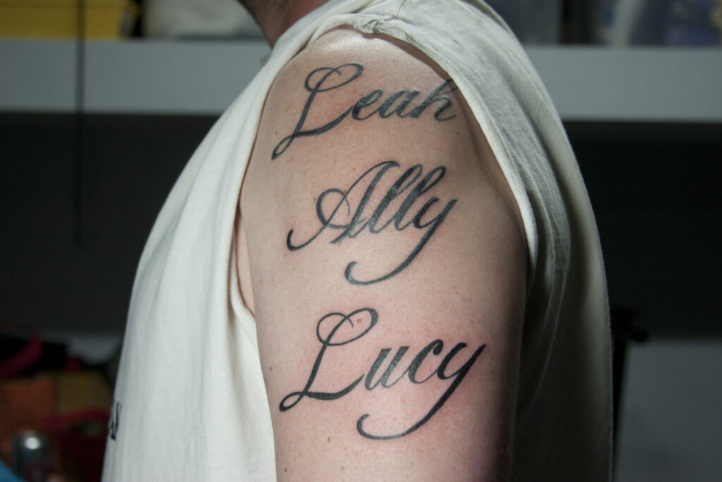 Legible name tattoos on arms, showcasing clear lettering visible even from across a room, highlighting good readability in text-based aesthetic tattoos.