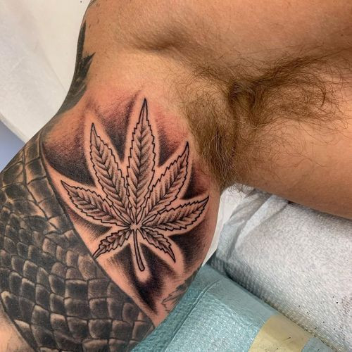 A minimalist pot leaf outline tattoo on a man's wrist, subtle and symbolic