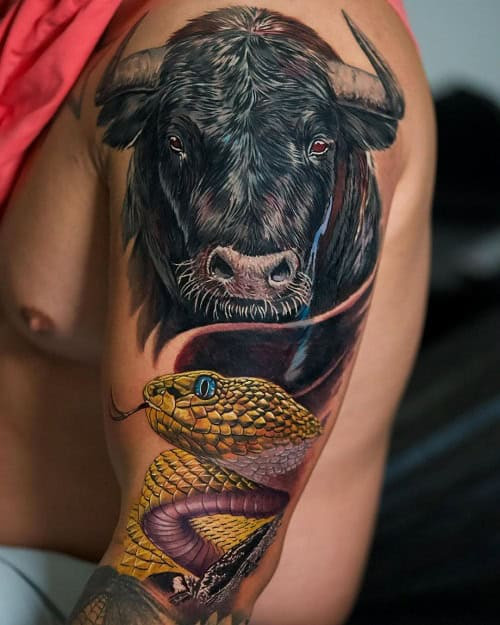 Highly realistic black and grey ink bull tattoo on the upper arm