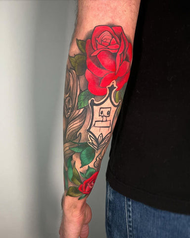 Vibrant red rose tattoo on a forearm with rich color saturation, showcasing the classic symbol of love and passion.