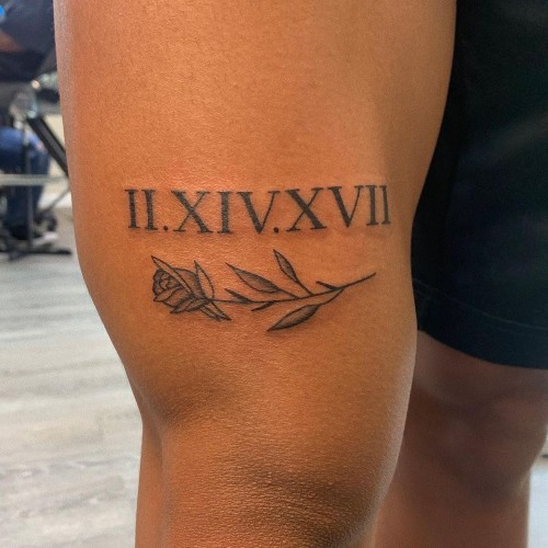 A Roman numeral tattoo incorporated into a design on a man's arm, subtle date commemoration