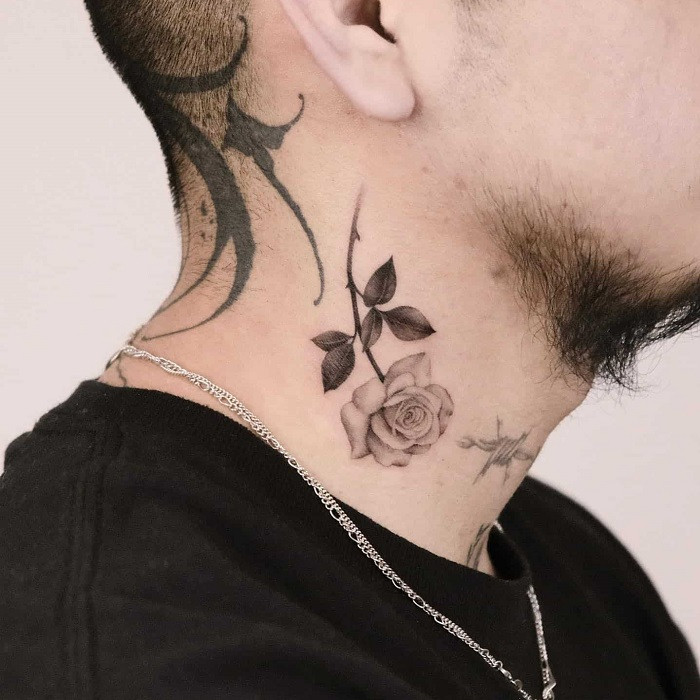 Red rose neck tattoo with vibrant petals and green leaves, symbolizing love and passion.