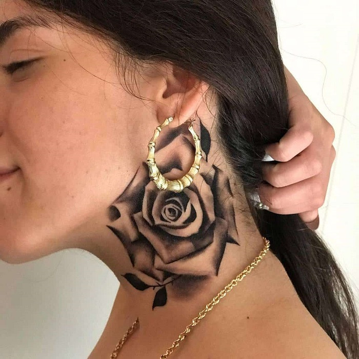 Small, delicate red rose outline tattoo behind the ear on the neck.