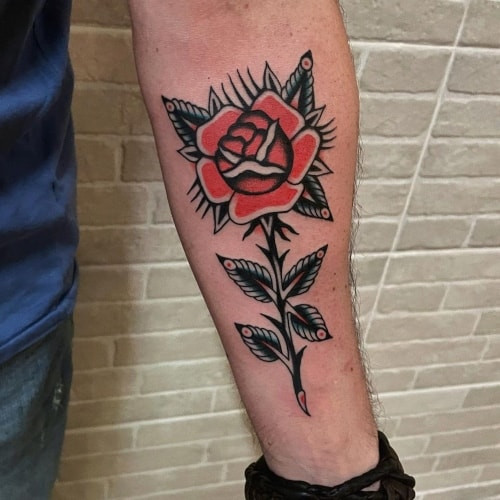 Two rose tattoos on men, one on the hand with a minimalist single rose outline and another on the forearm with a traditional red rose with leaves.