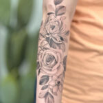 Detailed black and gray rose tattoo on a forearm, showcasing intricate petal work and shading.