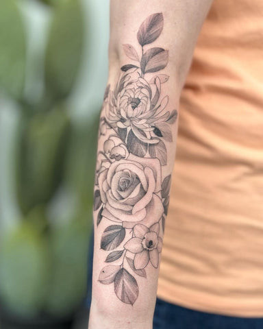 Detailed black and gray rose tattoo on a forearm, showcasing intricate petal work and shading.