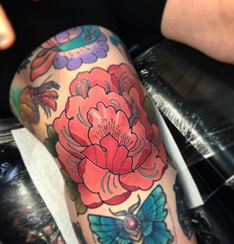 Floral knee tattoo featuring a pink peony design in vibrant colors, placed on the kneecap, showcasing the artistry of Hanah Elizabeth.