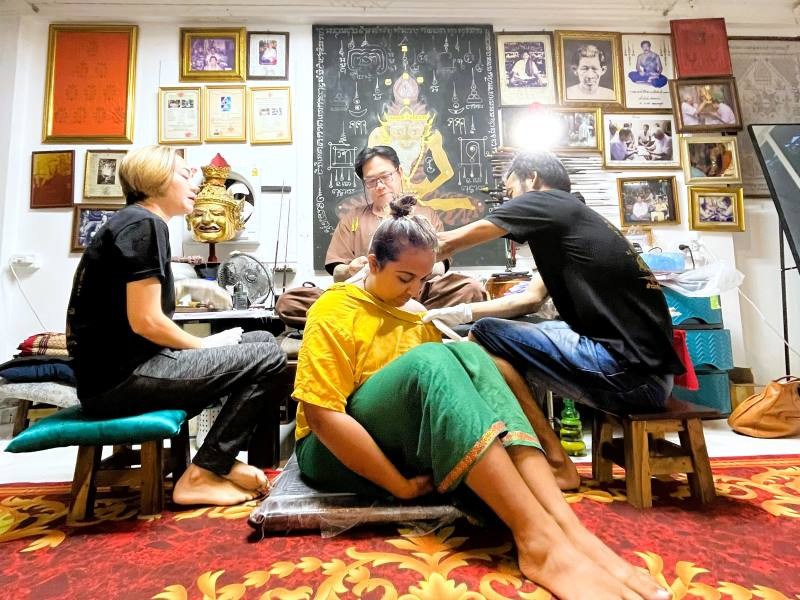 The author receiving her Sak Yant tattoo on her back, dressed modestly in accordance with Thai tradition.