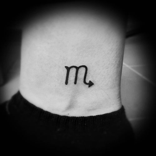 Scorpio symbol tattoo on the wrist, a minimalist zodiac men tattoo idea.