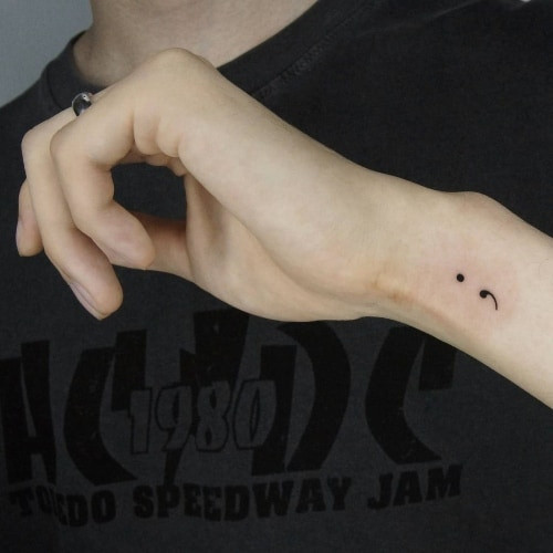 Two semicolon tattoos on men, one on the forearm with a semicolon and heart and another on the arm with a minimalist semicolon outline.