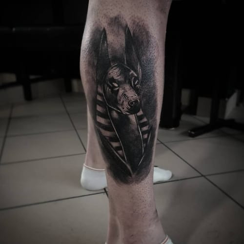 A shadow raven tattoo with dark ink on a man's leg, gothic and bold