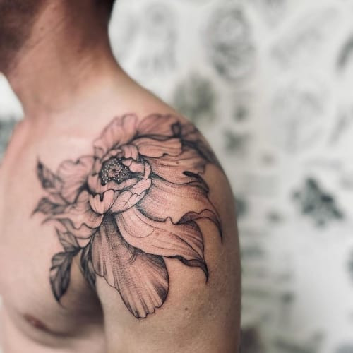 Shoulder tattoo with floral and geometric elements on a man's shoulder