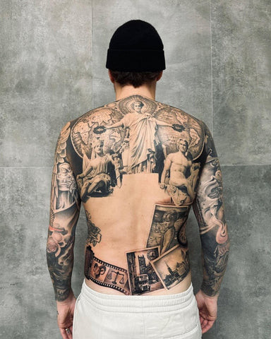 A man featuring a shoulder to back tattoo that extends across his upper back and shoulders