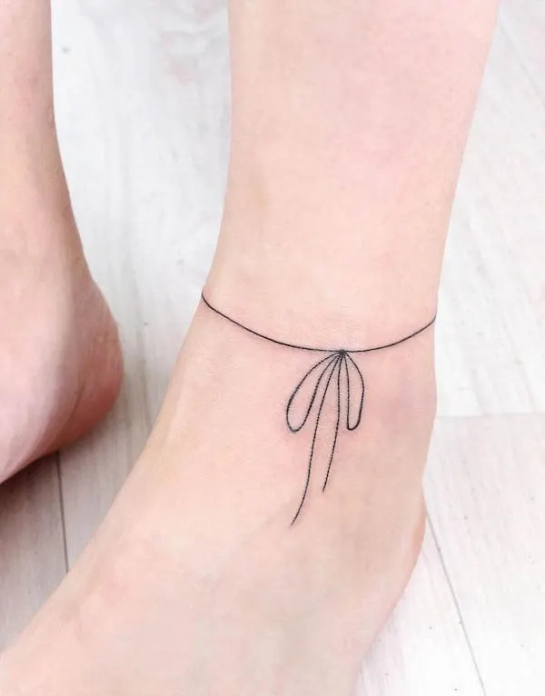 Delicate string anklet tattoo wrapping around the ankle with a ribbon, embodying minimalist and girly style