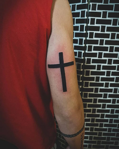 Simple cross tattoo on finger, small minimalist black ink design for men.