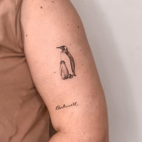 Simple penguin silhouette tattoo on leg, minimalist black ink design for men.