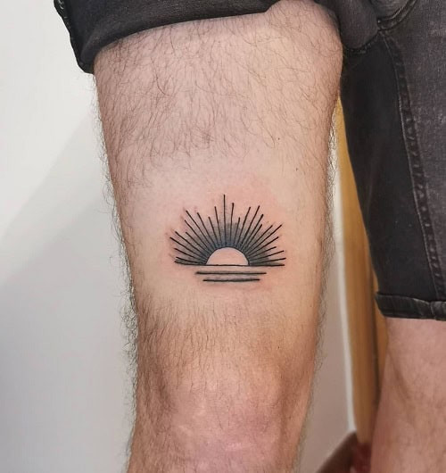 Simple sun tattoo on chest, minimalist black ink design for men.