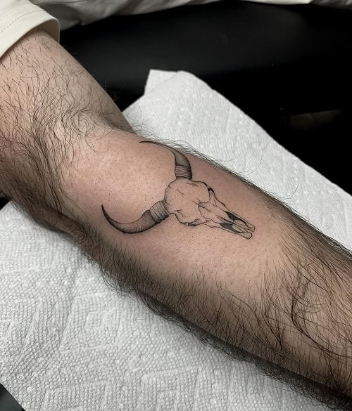 Minimalist fine line Taurus bull outline tattoo on the arm