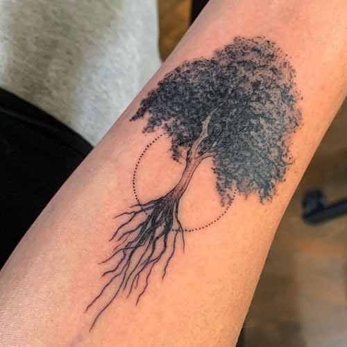 Simple tree outline tattoo on forearm, minimalist black ink design for men.