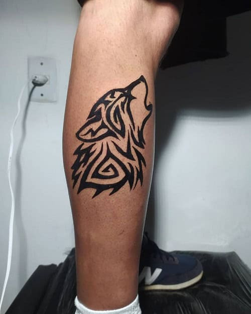 Simple tribal wolf head tattoo on arm, minimalist black ink design for men.