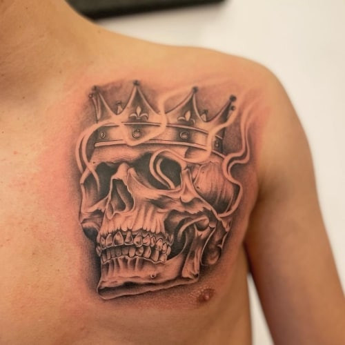 Two skull tattoos on men, one on the hand with a detailed sugar skull and another on the forearm with a realistic black and grey skull.