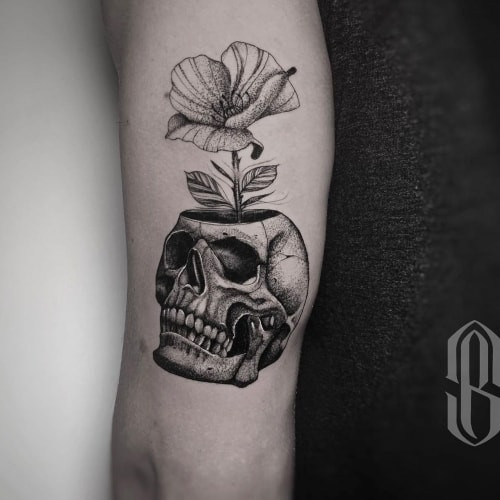 Black and grey skull tattoo with intricate shading on a man's hand