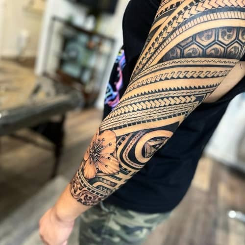 A full sleeve tattoo with detailed scenes on a man's arm, extensive and bold