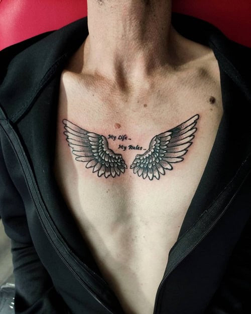 Small angel wings tattoo on a man's upper back