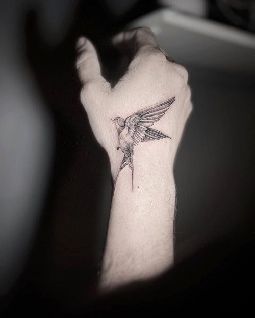 Discreet small bird tattoo for men on the wrist, ideal for subtle expression