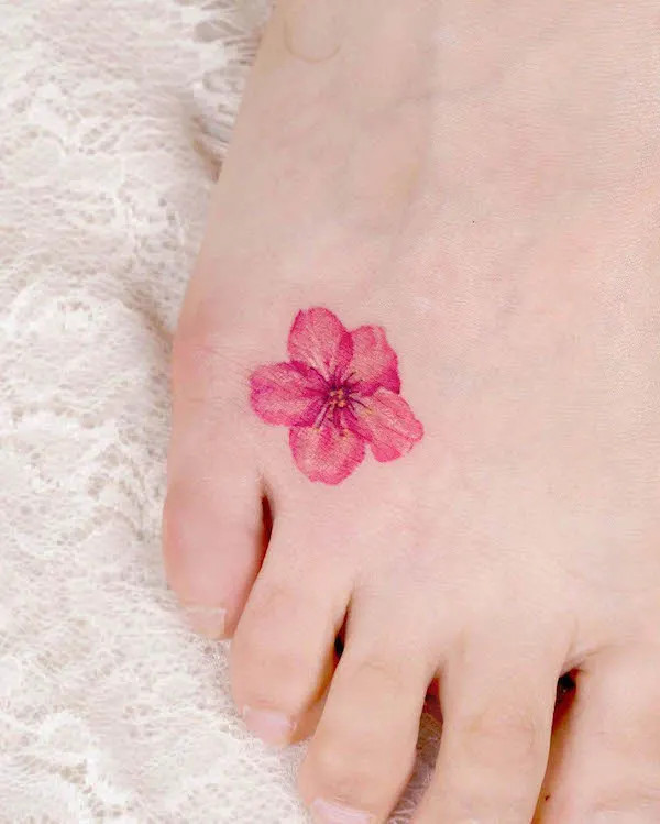 Tiny cherry blossom foot tattoo, a delicate and symbolic representation of the fleeting nature of time and life