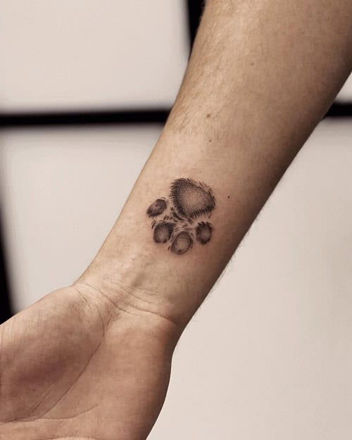 Small dog paw print tattoo in black ink on a man's chest