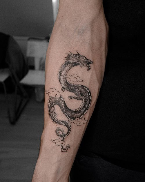 Small dragon tattoo in black ink with swirling lines on a man's arm