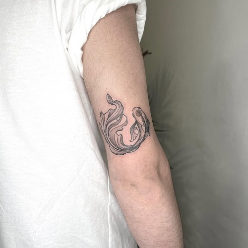 Small fish outline tattoo with minimalist style on a man's wrist