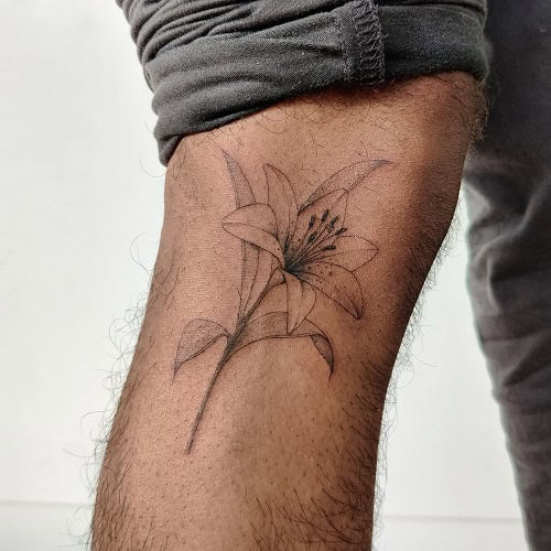 Small colorful flower tattoo with detailed petals on a man's hand