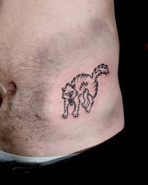 Small hip tattoo with a delicate design peeking from jeans on a man's hip