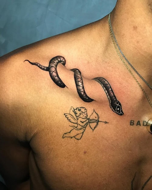 Small black snake tattoo coiled on a man's finger