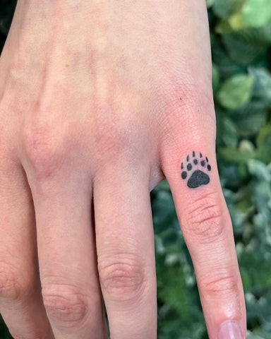 Small minimalist anchor tattoo on man's finger, representing stability and resilience