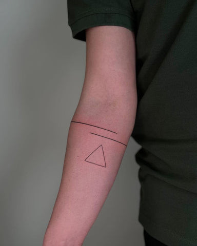 Simple black ink forearm tattoo of a small geometric design, showcasing a minimalist and subtle style.