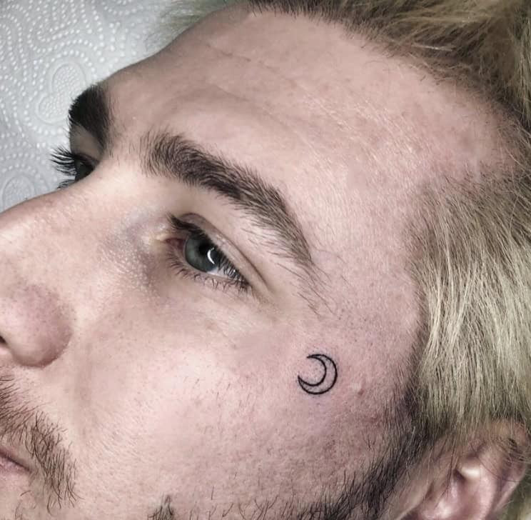 Small face tattoo with a minimalist symbol on a man's face