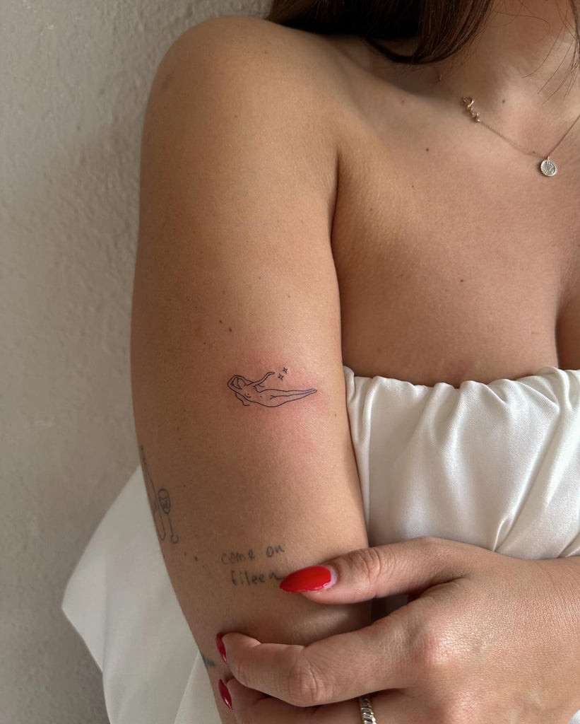 A minimalist line-art tattoo of a dog's face on a woman's forearm, celebrating pet love in a simple style.