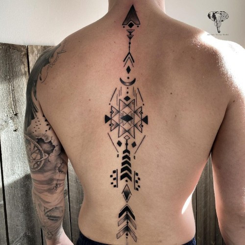 A spine tattoo with floral elements extending down a man's back, flowing and elegant