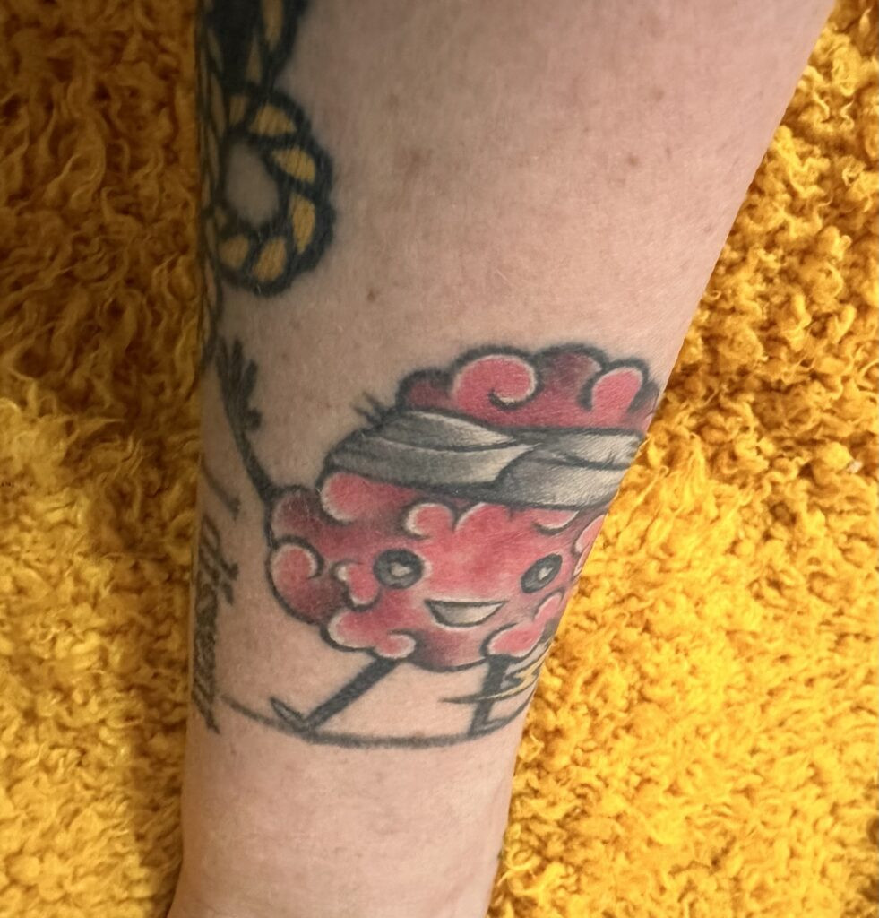 Stacy shares one of her tattoos, which is a colorful brain with arms and feet along with a lightning bolt and a head bandage.