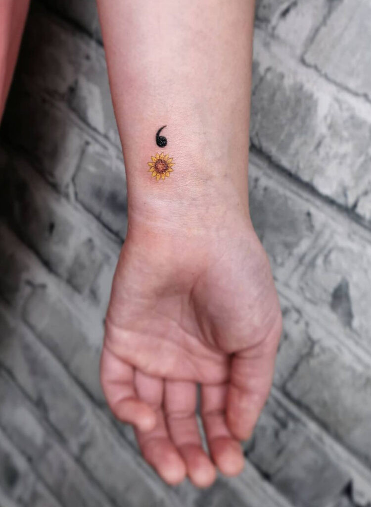 Tiny sunflower semicolon wrist tattoo