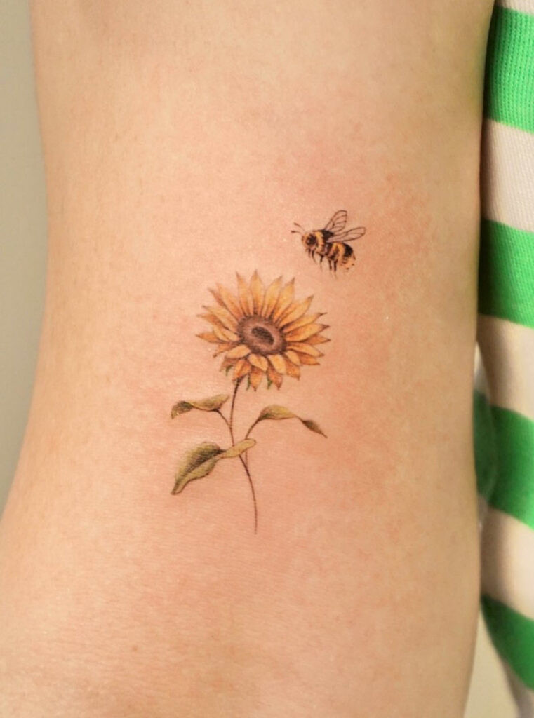 Tiny bee landing on a sunflower arm tattoo